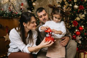 A man and a woman holding a baby in front of a christmas tree